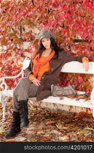 Autumn park scenery young woman relax on bench fashion model