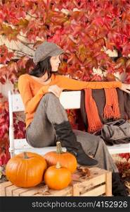 Autumn park young woman relax sitting on bench with pumpkins