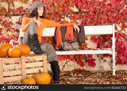 Autumn park young woman relax sitting on bench with pumpkins