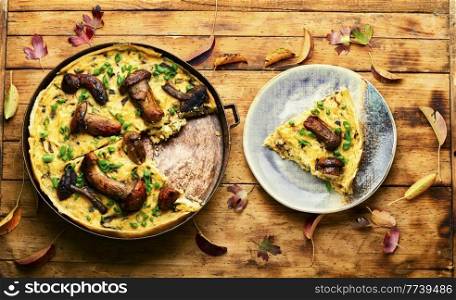 Autumn pie or quiche with forest mushrooms on rustic wooden table. Delicious pie with forest mushrooms