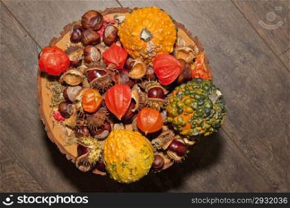 Autumn piece with calabashes, pumpkins, chestnuts and chinese lanterns on brown wood background