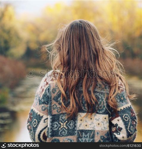 Autumn portrait of girl outdoors with curly hair. Back view. Image toned style instagram filters