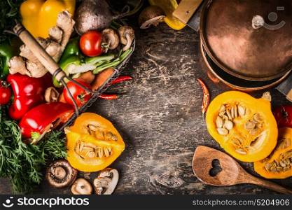 Autumn pumpkin dish cooking preparation with cooking pot ,vegetables and mushrooms on rustic wooden background, top view, frame. Vegetarian healthy food and eating concept