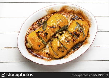 Autumn pumpkin roasted with sage, thyme and garlic. Pumpkin baked with herbs on the plate. Baked pumpkin with spice herbs
