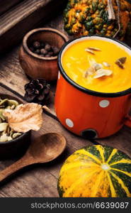 Autumn pumpkin soup in a metal cup. Autumn food. Pumpkin cream soup in mug