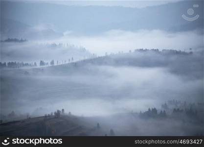 Autumn rain and mist in mountains. Morning fog over hills and forest. Thick fog around mountain tops. Fall background