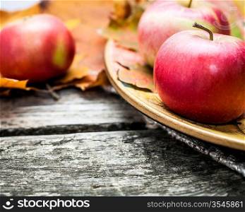Autumn red apples and maple leaves on old wooden table. Thanksgiving day concept. Macro shot, very shallow depth of fields