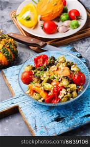 Autumn salad from baked vegetables. Salad from pumpkin, Brussels sprouts, tomatoes and onions. Baked vegetable salad