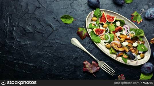Autumn salad with plums,figs,olives and cheese.Seasonal salad of fruits and nuts.Space for text. Autumn seasonal salad with plums and figs