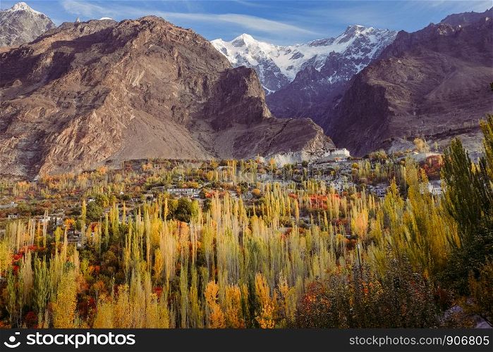 Autumn scene in Hunza valley with a view of Baltit fort on the hill and snow capped Karakoram mountain range in the background, Karimabad. Gilgit Baltistan, Pakistan.
