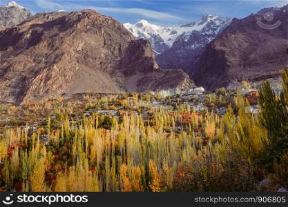 Autumn scene in Hunza valley with a view of Baltit fort on the hill and snow capped Karakoram mountain range in the background, Karimabad. Gilgit Baltistan, Pakistan.