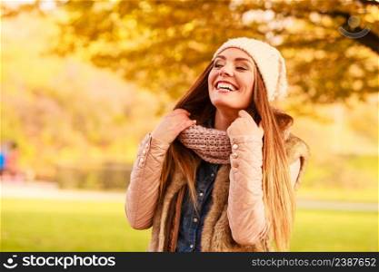 Autumn season. Smiling attractive woman relaxing outdoors in autumnal park, enjoying sunny day. Trendy girl in warm fashionable clothing outside. Smiling woman relaxing outdoor in autumnal park