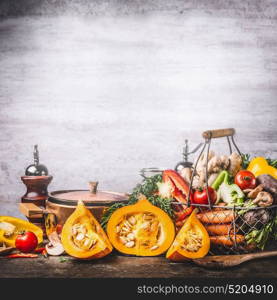 Autumn seasonal food still life with pumpkin, mushrooms, various organic harvest vegetables and cooking pot on rustic kitchen table background, front view. Vegetarian healthy eating concept, square