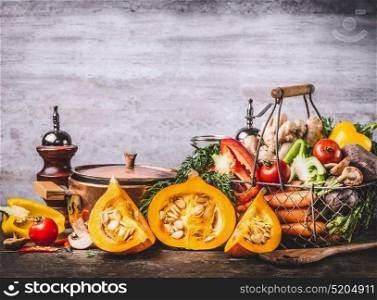 Autumn seasonal food still life with pumpkin, mushrooms, various organic harvest vegetables and cooking pot on rustic kitchen table background, front view. Vegetarian healthy eating concept