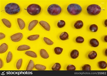 Autumn setting of organic in shell nuts and fruits on yellow background