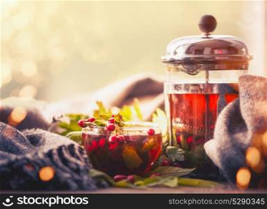 Autumn still life with cup and tea pot with berries, scarf and fall leaves at sunny bokeh background