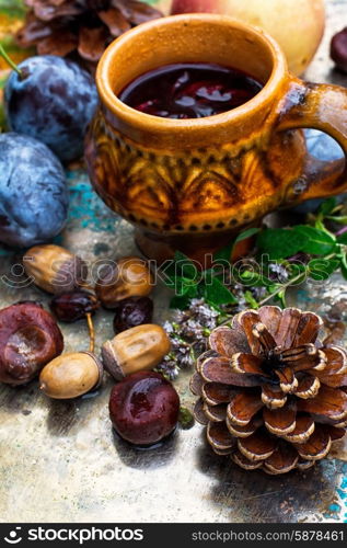 Autumn still life with tea.. Stylish cup of autumn tea infused with herbs on the background of the fruit