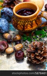 Autumn still life with tea.. Stylish cup of autumn tea infused with herbs on the background of the fruit