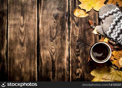 Autumn style. A Cup of hot coffee with mittens. On a wooden table.. Autumn style. A Cup of hot coffee with mittens.