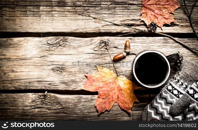 Autumn style. A Cup of hot coffee with mittens. On a wooden table.. Autumn style. A Cup of hot coffee with mittens.