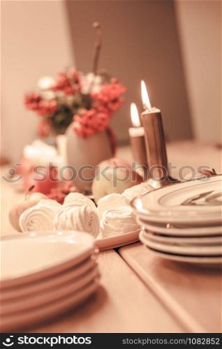 Autumn table decoration for Holiday Thanksgiving dinner. Cozy warm natural style with zephyr marshmallow sweets, candles lights, red berries and apples