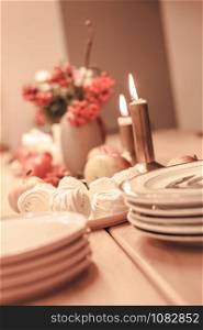 Autumn table decoration for Holiday Thanksgiving dinner. Cozy warm natural style with zephyr marshmallow sweets, candles lights, red berries and apples