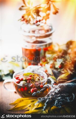 Autumn tea with red berries , tea pot , leaves and scarf at window