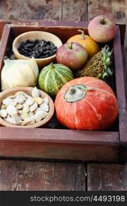 Autumn vegetables and fruits. Wooden box with autumn harvest decorative pumpkins and pumpkin seeds