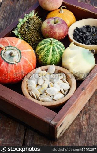 Autumn vegetables and fruits. Wooden box with autumn harvest decorative pumpkins and pumpkin seeds