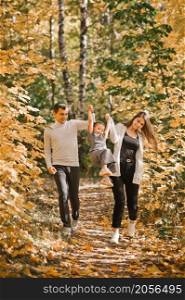 Autumn walk of a young family in the forest.. Dad, mom and daughter are walking in the autumn forest 3369.