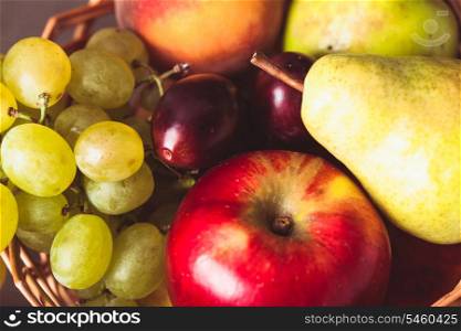 Autumnal fruits in the basket as a background