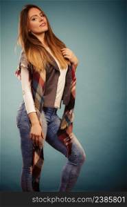 Autumnal look concept. Fashionable young woman wearing warm autumn clothing woolen checked scarf, denim pants. Fashionable girl in autumn warm clothing