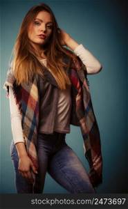 Autumnal look concept. Fashionable young woman wearing warm autumn clothing woolen checked scarf, denim pants. Fashionable girl in autumn warm clothing