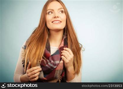 Autumnal outfit concept. Lovely young long haired woman wearing warm autumn clothing woolen checked scarf on blue. Woman wearing woolen checked scarf warm autumn clothing