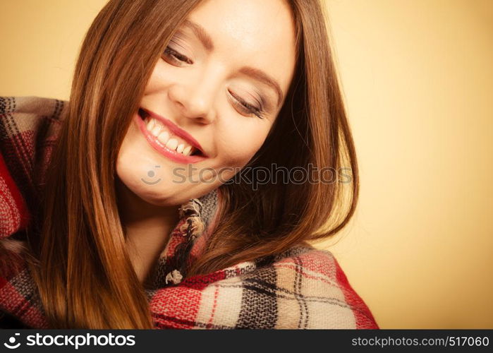 Autumnal outfit concept. Young long haired woman wearing warm autumn clothing woolen checked scarf on beige, studio shot. Woman wearing woolen checked scarf warm autumn clothing