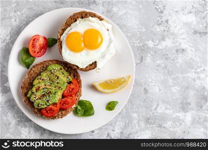 Avicado toast. Egg sandwich appetizer. Top view of balanced brunch food with rye bread. Healthy vegetarian dish recipe with tomato, basil and chili. Gourmet snack. Fitness vegan burger. Copy space. Avicado toast. Egg sandwich appetizer. Top view