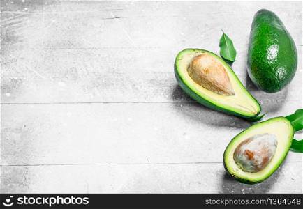 Avocado and avocado halves. On white rustic background.. Avocado and avocado halves