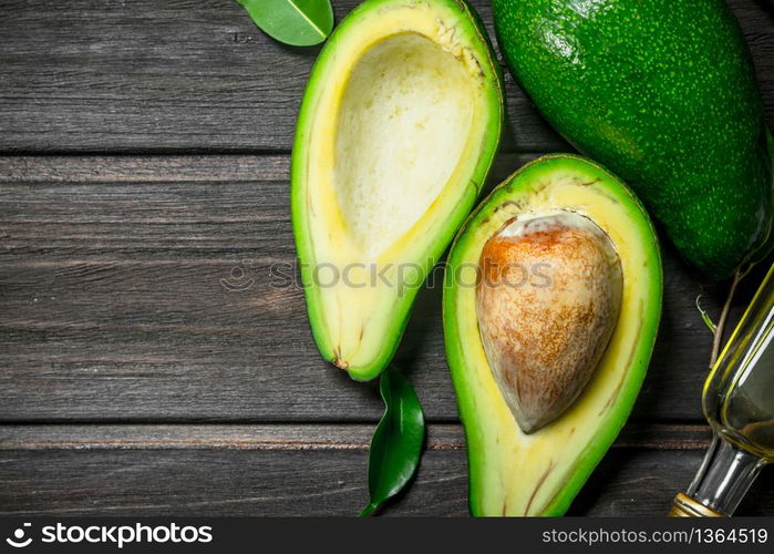 Avocado and avocado oil. On a black wooden background.. Avocado and avocado oil.