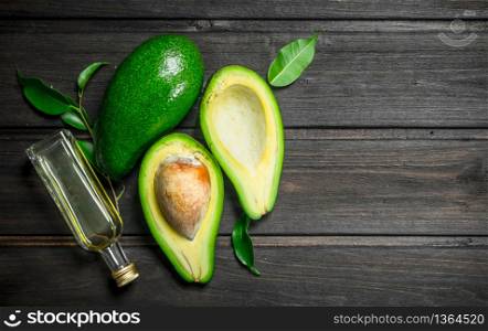 Avocado and avocado oil. On a black wooden background.. Avocado and avocado oil.