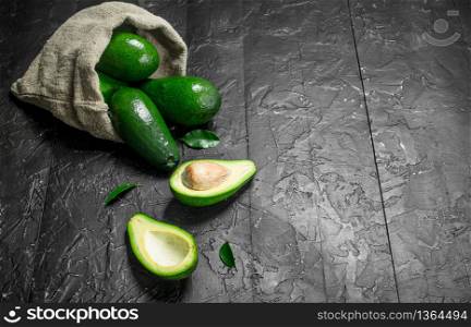 Avocado and avocado slices in an old bag. On rustic background.. Avocado and avocado slices in an old bag.