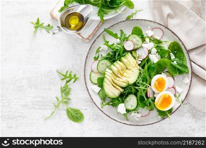 Avocado and boiled egg fresh vegetable salad with radish, cucumber, spinach, arugula and cottage cheese. Top view