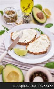 Avocado and cream cheese toasts preparation - grilled or toasted bread with cheese smeared .. Avocado and cream cheese toasts preparation - grilled or toasted bread with cheese smeared 