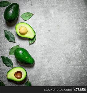 Avocado and leaves on a stone background.. Avocado and leaves on stone background.