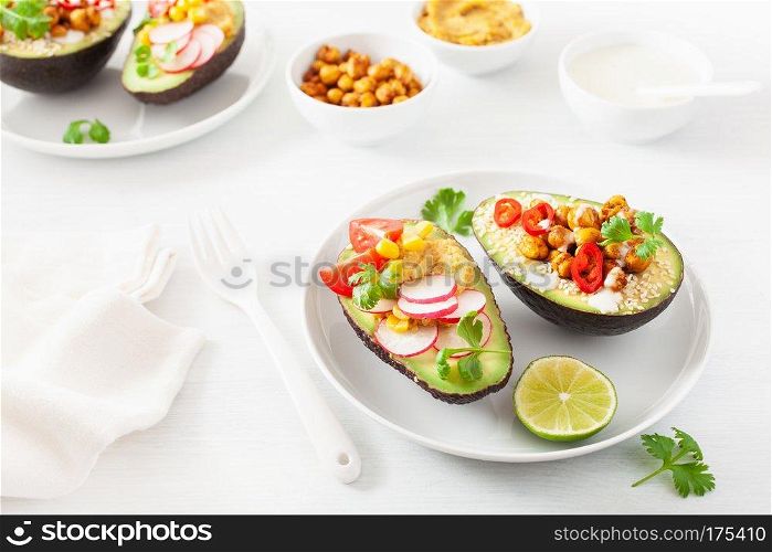 avocado boats stuffed with hummus, tomatoes, radish, roasted chickpea