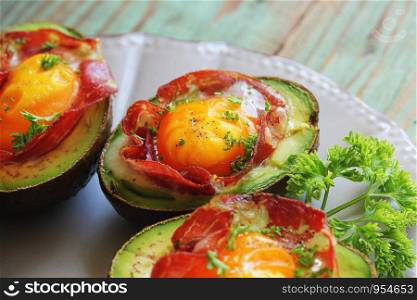 Avocado Egg Boats with bacon on dark wooden background. Top view