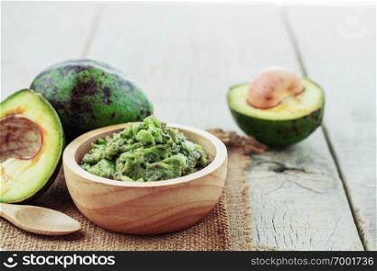 Avocado in a bowl on wooden floor.