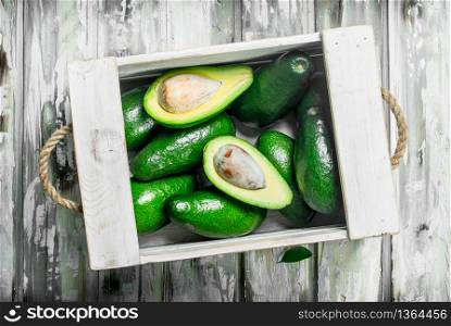 Avocado in a white box. On a white wooden background.. Avocado in a white box.