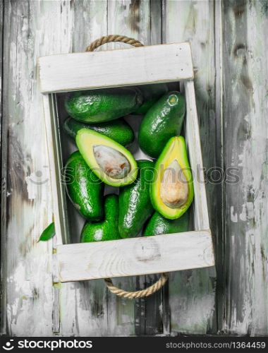 Avocado in a white box. On a white wooden background.. Avocado in a white box.