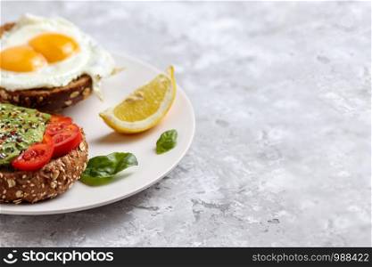 Avocado meal. Healthy egg toast on rye bread with tomato. Vegetarian brunch dish. Delicious green burger recipe for breakfast. Snack with tomatoes and basil. Organic fitness lunch food. Copy Space. Avocado meal. Healthy egg rye bread toast. Brunch