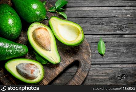 Avocado on a chopping Board. On a black wooden background.. Avocado on a chopping Board.